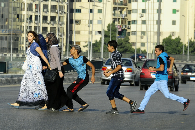 A young Egyptian man grabs a woman crossing the street with her friends in Cairo. Vigilante groups are now taking to the streets and spray-painting the clothes of the harassers.