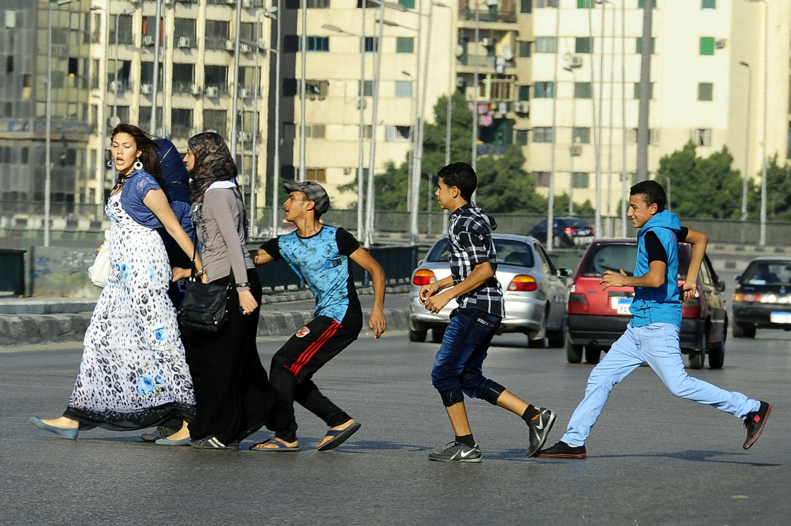 A young Egyptian man grabs a woman crossing the street with her friends in Cairo. Vigilante groups are now taking to the streets and spray-painting the clothes of the harassers.
