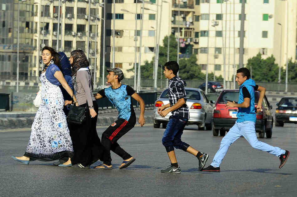 A young Egyptian man grabs a woman crossing the street with her friends in Cairo. Vigilante groups are now taking to the streets and spray-painting the clothes of the harassers.