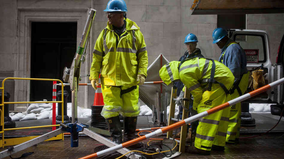 Consolidated Edison workers try to repair damage near the New York Stock Exchange on Tuesday. Consolidated Edison workers try to repair damage near the New York Stock Exchange on Tuesday.