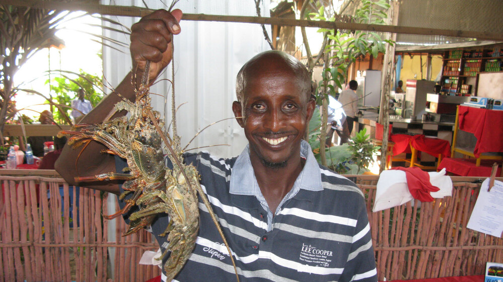Somali chef Ahmed Jama holds up freshly caught spiny lobsters he's about to cook in one of his restaurants in Mogadishu.