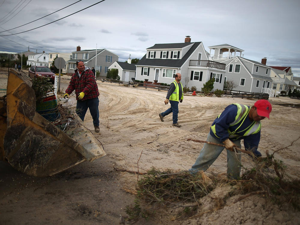 Workers clean up debris left by Superstorm Sandy in Long Beach Island, N.J., on Wednesday. The storm may lead to layoffs as business losses mount, but also could result in hiring related to rebuilding.