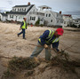 Workers clean up debris left by Superstorm Sandy in Long Beach Island, N.J., on Wednesday. The storm may lead to layoffs as business losses mount, but also could result in hiring related to rebuilding.