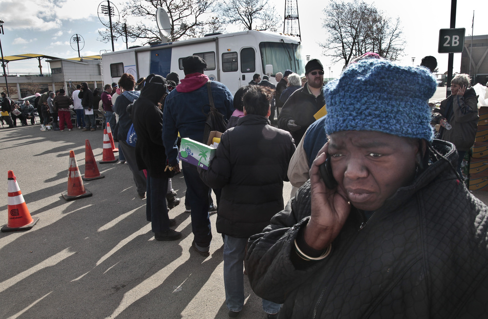 Evangean Pugh, far right, talks on a phone as she waits in line to apply for recovery assistance at a FEMA processing center in Coney Island, in the Brooklyn borough of New York.