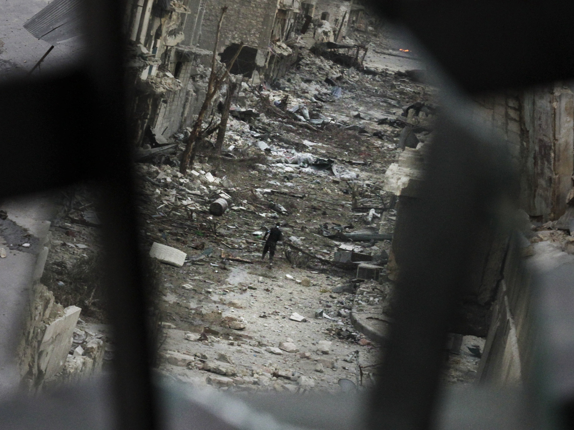 In Aleppo, Syria, this week: A rebel crossed a ruined street. This image shows him in a mirror's reflection.