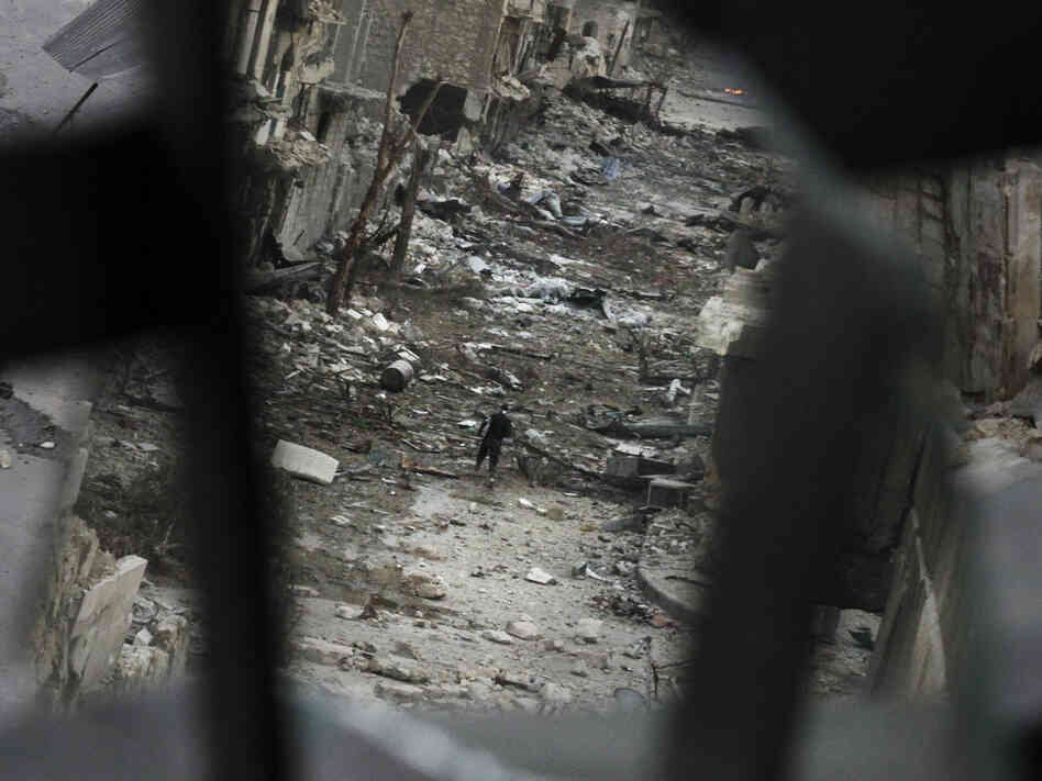 In Aleppo, Syria, this week: A rebel crossed a ruined street. This image shows him in a mirror's reflection.