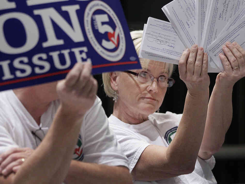 Melissa Fults, treasurer for Arkansans for Compassionate Care, holds up cards at the back of a news conference in Little Rock, Ark., with the names of doctors she says support a ballot issue that would legalize medical marijuana.