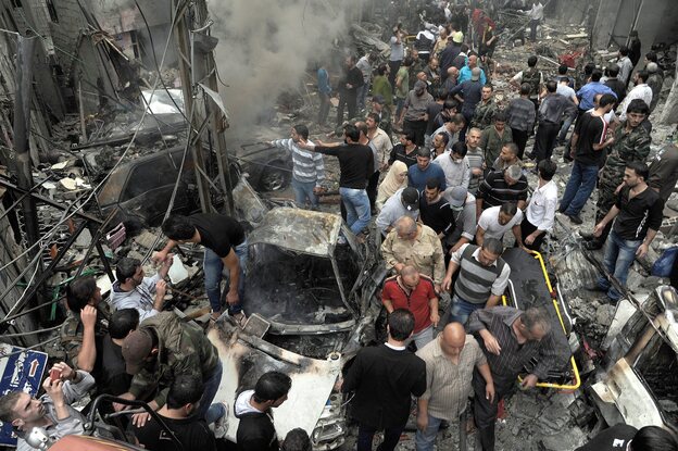 Syrians gather at the site of a car bombing Monday that killed 11 people and wounded dozens in Damascus, according to the SANA news agency, which provided the photo. The violence in the city was described as some of the worst in recent months.