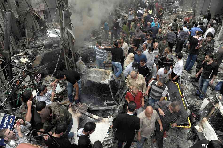 Syrians gather at the site of a car bombing Monday that killed 11 people and wounded dozens in Damascus, according to the SANA news agency, which provided the photo. The violence in the city was described as some of the worst in recent months.