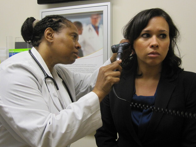 Dr. Wanda Simmons-Clemmons examines Dawn Antonelli at the PromptCare urgent care clinic.