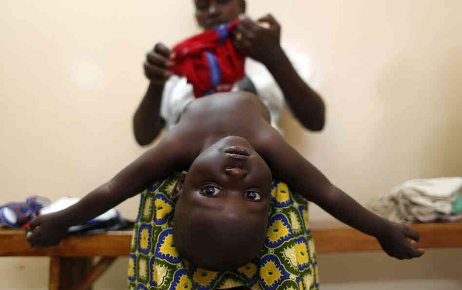 A mother dresses her baby after doctors examined him during the malaria vaccine trial at the Walter Reed Project Research Center in Kombewa in Western Kenya in October 2009.