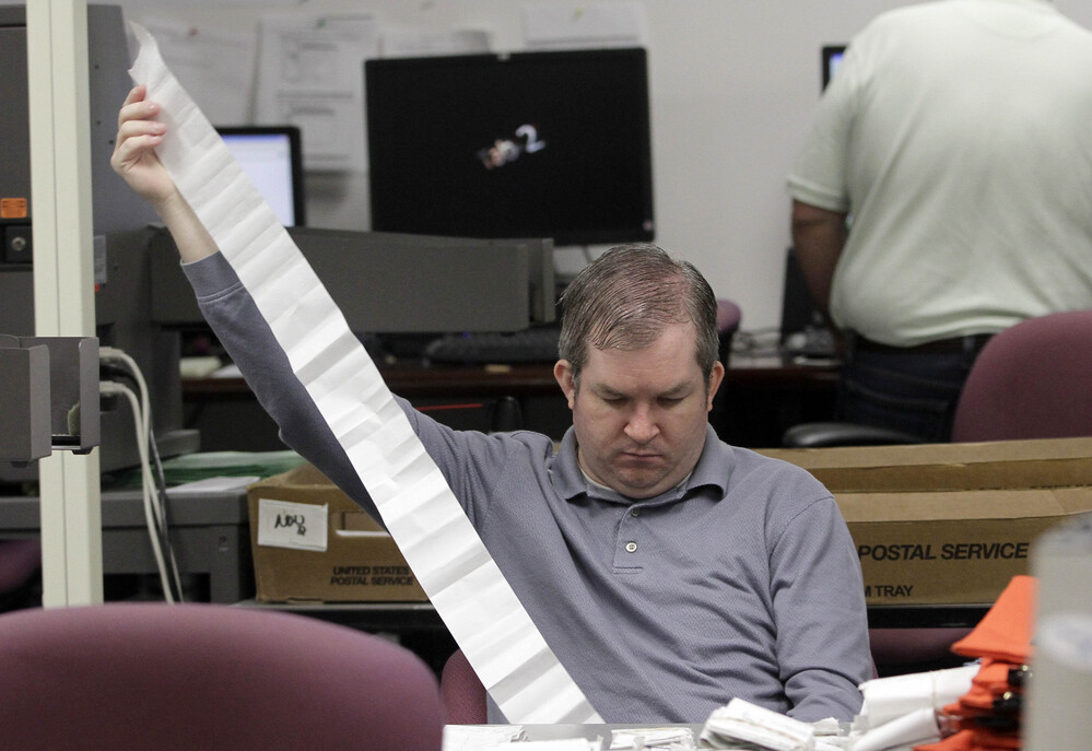 A Miami-Dade Elections Department employee tallies absentee ballot reports in Doral, Fla., on Thursday.