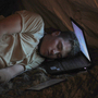 U.S. Army Pvt. Freymond Tyler sleeps on a laptop next to his gun at combat outpost Makuan in Kandahar province, Afghanistan, in 2011.