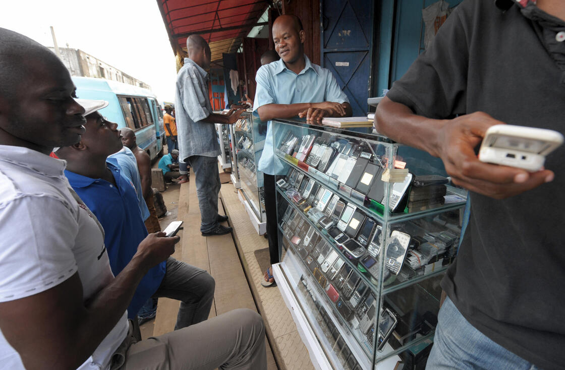 Men look at mobile phones at the Adjame market in Abidjan, Ivory Coast. The market for mobile telephones in developing countries has grown quickly, and now Facebook and Google are trying to get users to use the Internet on their devices.