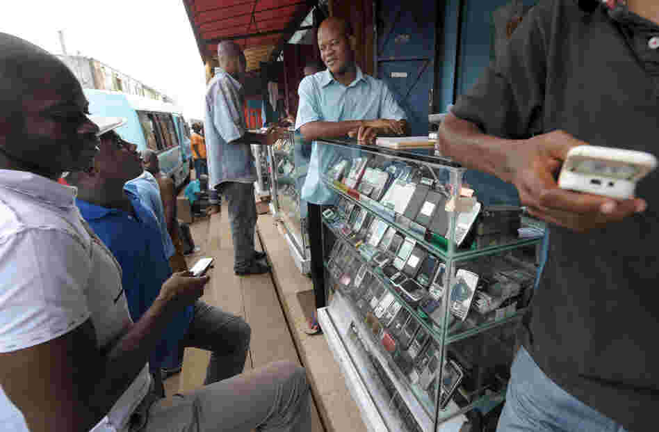 Men look at mobile phones at the Adjame market in Abidjan, Ivory Coast. The market for mobile telephones in developing countries has grown quickly, and now Facebook and Google are trying to get users to use the Internet on their devices.