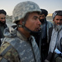 Afghan villagers look at a translator as U.S. soldiers tend to an injured local Afghan man, who was shot for being suspected of planting a roadside bomb in Genrandai village at Panjwai district, Kandahar, on Sept. 24.