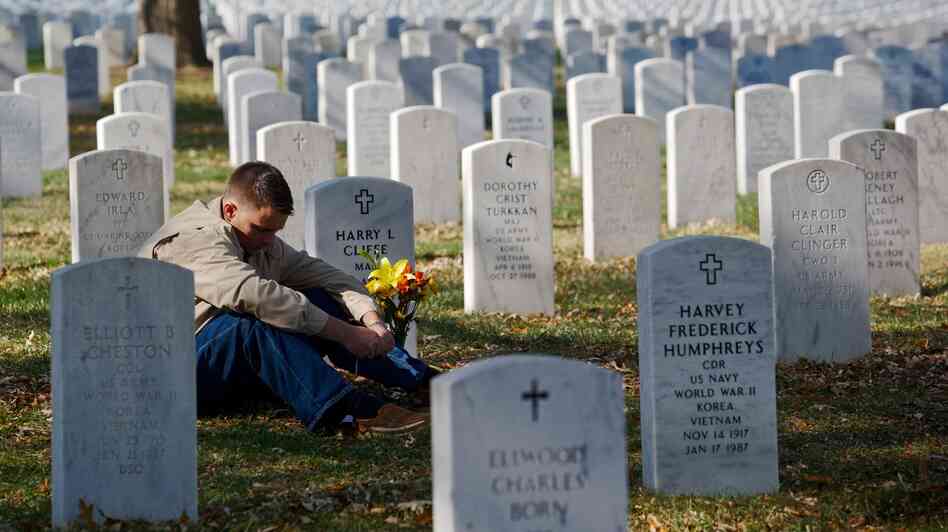 Marine Corps Capt. Jeff Cliffe, sat to reflect Sunday next to the grave of his grandfather and grandmother at Arlington National Cemetery in Virginia.
