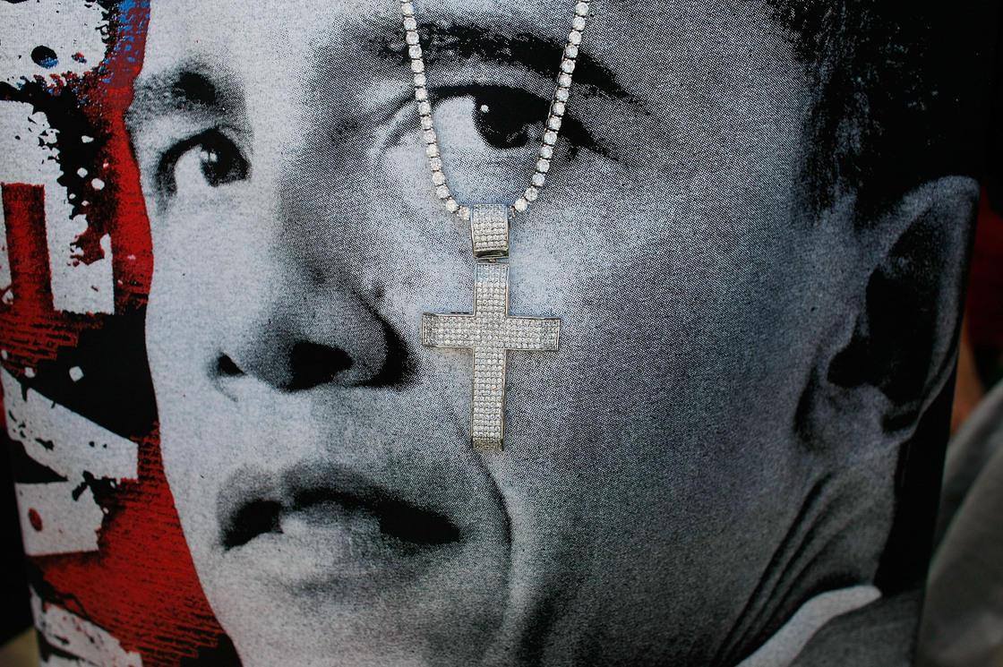 A cross hangs in front of a T-shirt printed with Barack Obama's face at a 2008 campaign event in Las Vegas.