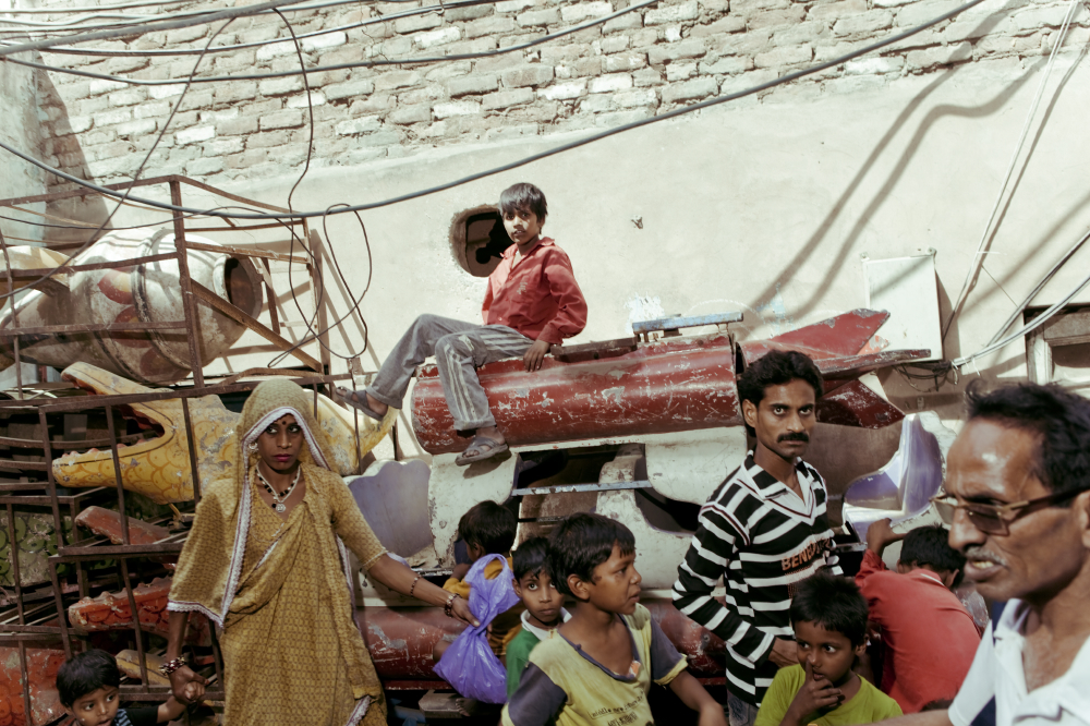 Stacks of carousel seats sit in Kathputli's alleyways and have become makeshift jungle gyms for the children. Laws have been implemented to limit street performance, and the artists have had to rely on other means to make money.