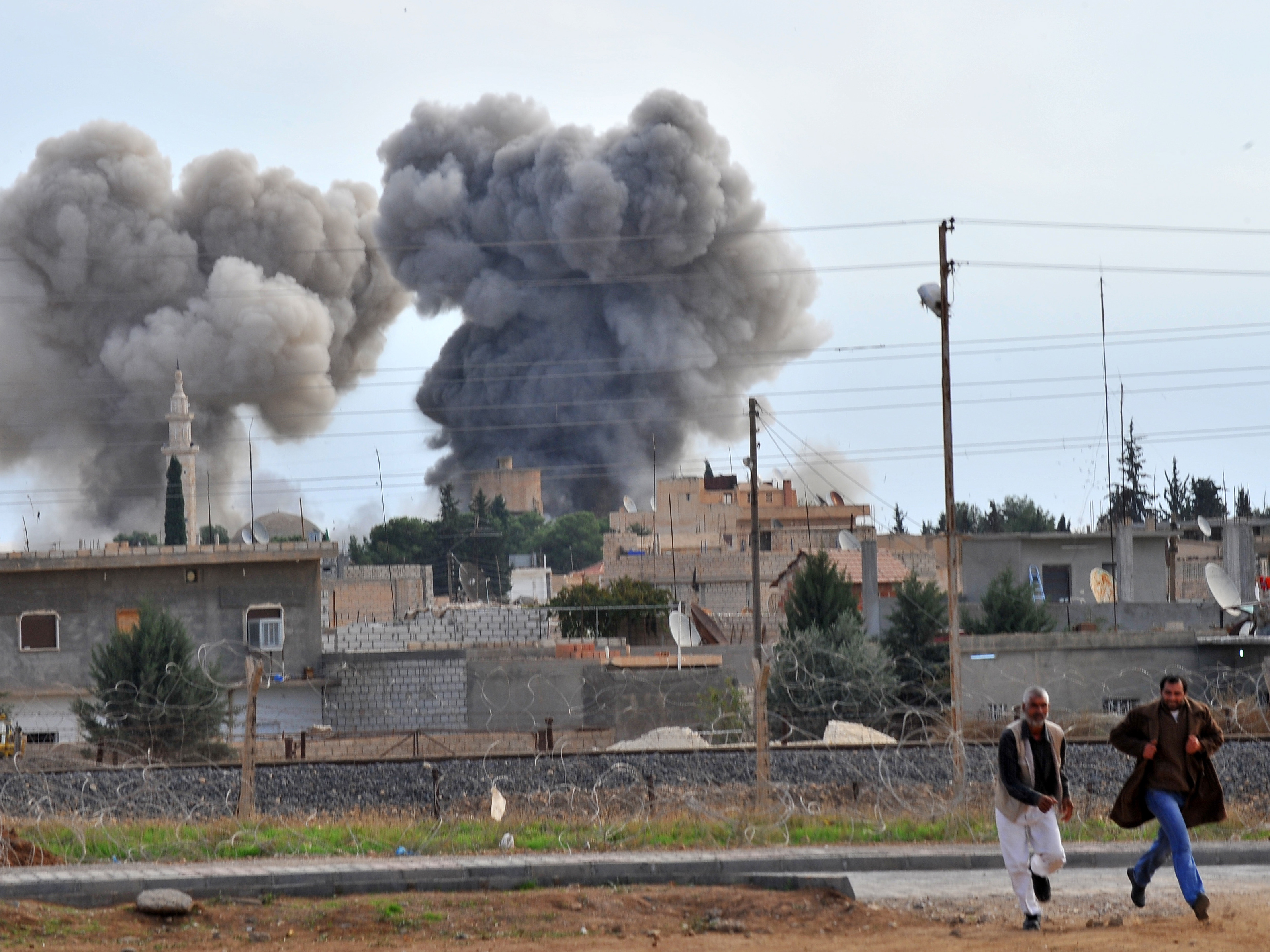 A picture taken from the adjacent Turkish border town of Ceylanpinar shows people running in front of smoke after a Syrian aircraft bombed the strategic border town of Ras al-Ain earlier today. A picture taken from the adjacent Turkish border town of Ceylanpinar shows people running in front of smoke after a Syrian aircraft bombed the strategic border town of Ras al-Ain earlier today.