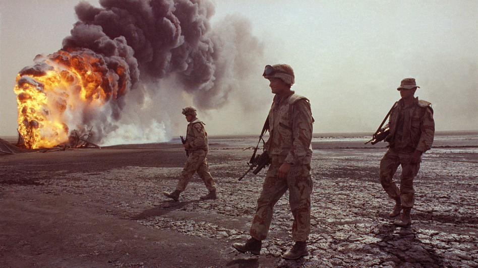 A U.S. Marine patrol walks across the charred oil landscape near a burning well near Kuwait City in March 1991. Concerns about oil supply were at play when the U.S. and its allies intervened during the Iraqi invasion of Kuwait in 1990. But American policy is changing now that Mideast oil imports to the U.S. are declining.