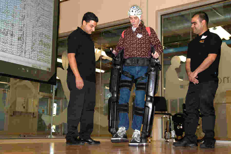 Steve Holbert (center), a paraplegic, demonstrates NeuroRex, a bionic exoskeleton suit augmented with a neural interface cap, developed by researchers at the University of Houston. Holbert controlled the robot's movements with his thoughts.