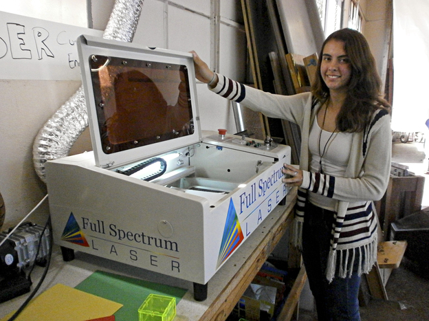 Jessie Davidson shows the school's laser cutter, which is used to burn the school insignia onto plastic objects, among other things.