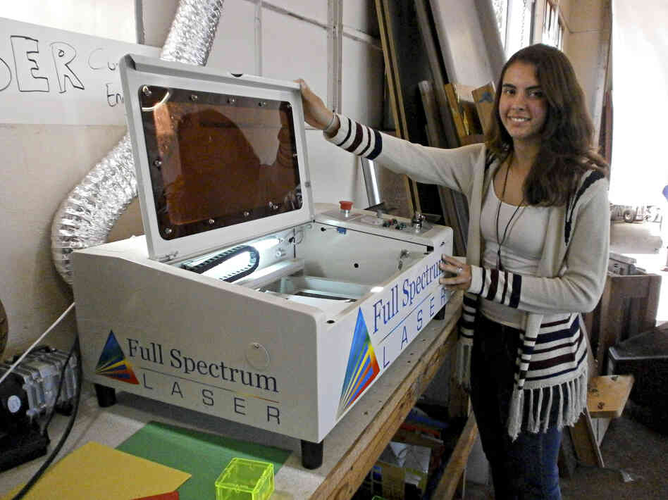 Jessie Davidson shows the school's laser cutter, which is used to burn the school insignia onto plastic objects, among other things.