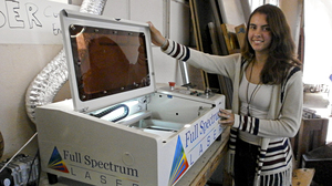 Jessie Davidson shows the school's laser cutter, which is used to burn the school insignia onto plastic objects, among other things.
