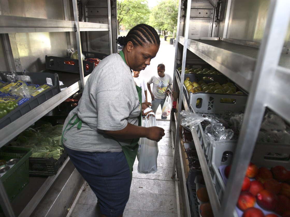 Peaches & Greens driver Diane Brown helps customers out of her truck in Detroit where she sells fresh fruits and vegetables.
