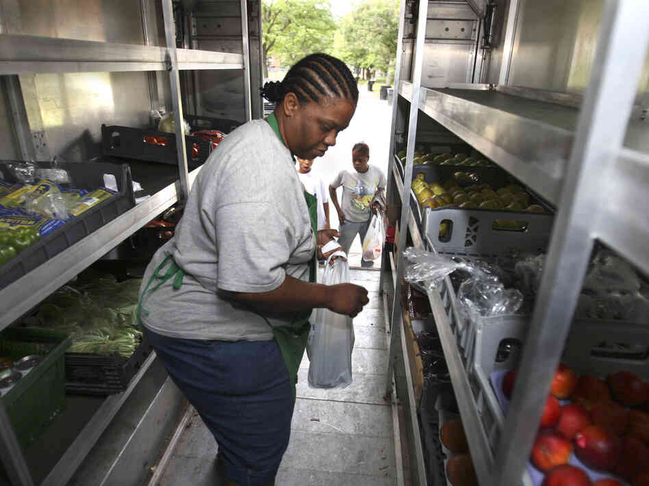 Peaches & Greens driver Diane Brown helps customers out of her truck in Detroit where she sells fresh fruits and vegetables.