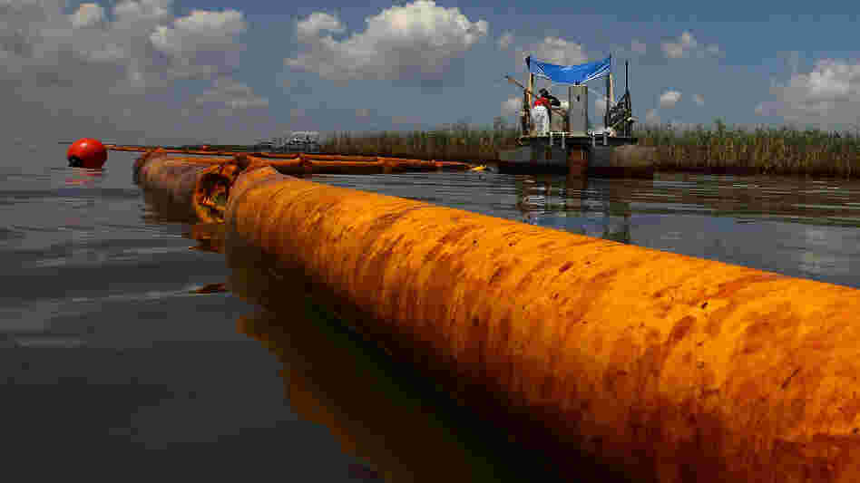 June 2010: A boom floats in the water as contract workers from BP use skimmers to clean oil from a marsh near Venice, La.
