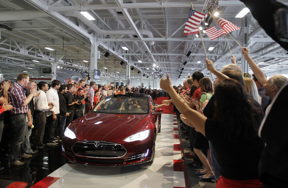 Tesla workers cheer on the first Tesla Model S cars sold during a rally at the Tesla factory in Fremont, Calif., in June.
