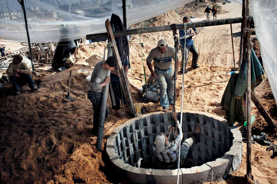 A new tunnel owner, in [a] white cap, watches his son descend into a well shaft to continue digging. Wealthy owners can afford mechanized winches, but this man, who saved for years to get a share of the tunnel trade, must rely on his family and a horse.