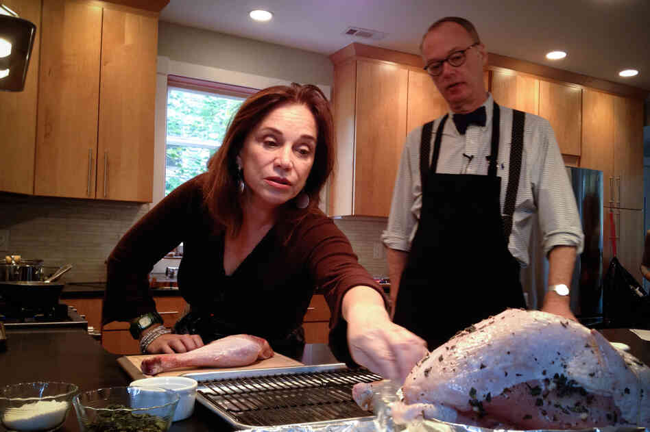 Morning Edition's Renee Montagne reaches for the prepared turkey as Kimball explains how Child's recipe calls for the turkey breast to be butterflied and separated from the thighs and legs and cooked in different pans.