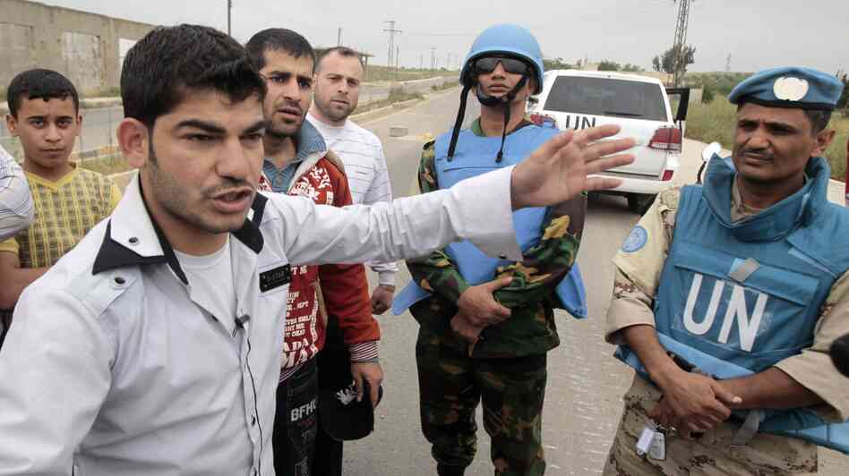 Supporters of President Bashar Assad speak with U.N. monitors who were arriving in the town in May. The monitors have since left.