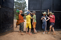 Boys hang out by the gate guarding the Kabanga Protectorate Center, as a local village girl walks by outside, in Kabanga, Tanzania.