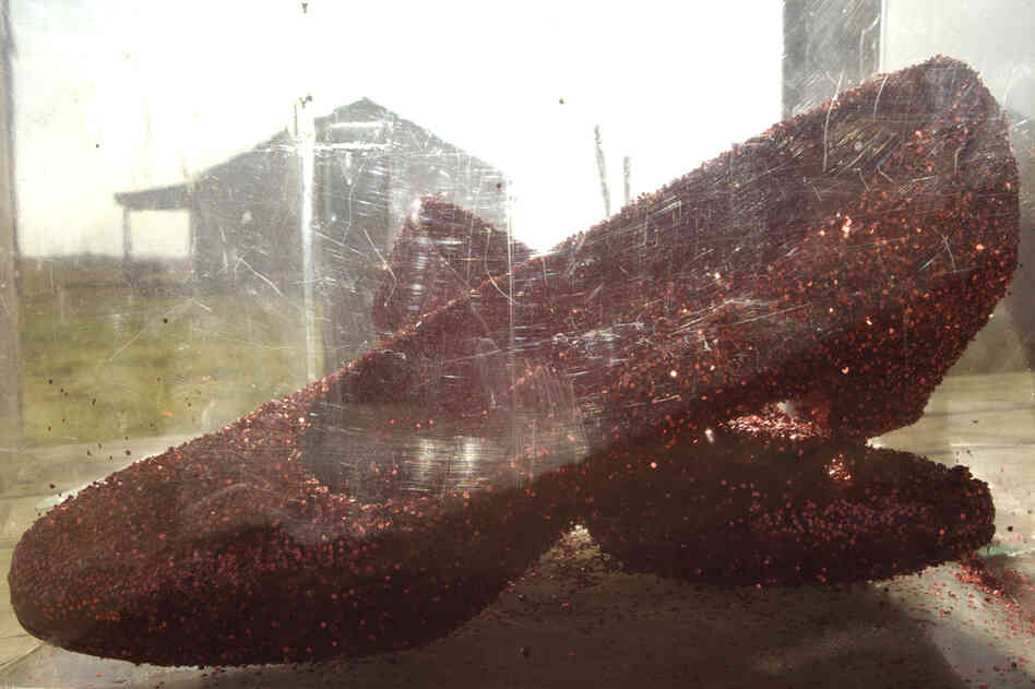 "Early one morning I was driving past a row of abandoned workers' houses when I spotted a pair of women's shoes on a porch. In a Lucite box, covered in ruby red glitter, they glowed like broken glass." "Early one morning I was driving past a row of abandoned workers' houses when I spotted a pair of women's shoes on a porch. In a Lucite box, covered in ruby red glitter, they glowed like broken glass."