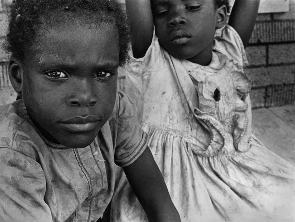 "The young daughters of Reverend Lander relax on the porch of their home on a hot day in 1970 in Hughes, Ark."