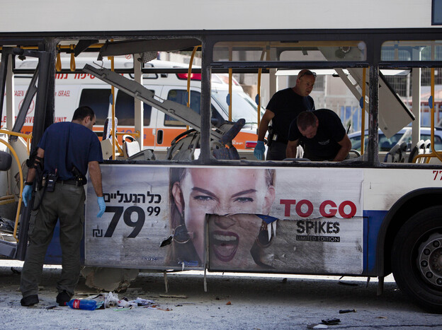 Israeli police officers examine a blown up bus at the site of a bombing in Tel Aviv on Wednesday.