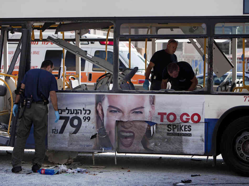 Israeli police officers examine a blown up bus at the site of a bombing in Tel Aviv on Wednesday.