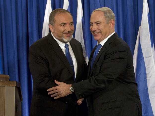 Israeli Prime Minister Benjamin Netanyahu (right) and Foreign Minister Avigdor Lieberman shake hands in front of the media after giving a statement in Jerusalem last month. Netanyahu said his Likud Party will join forces with the hard-line party of his foreign minister in upcoming parliamentary elections.