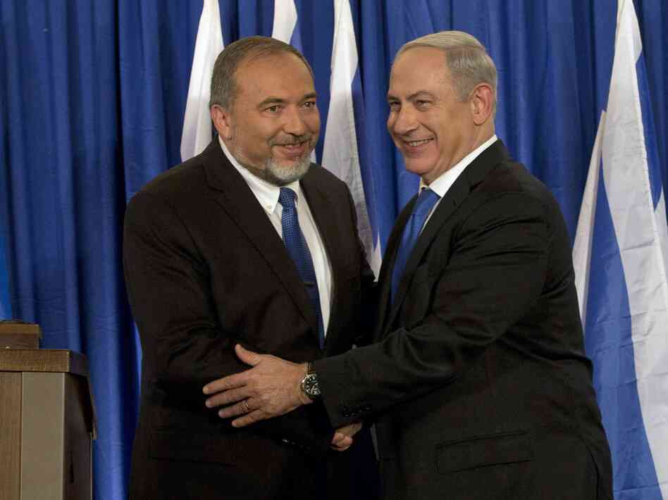 Israeli Prime Minister Benjamin Netanyahu (right) and Foreign Minister Avigdor Lieberman shake hands in front of the media after giving a statement in Jerusalem last month. Netanyahu said his Likud Party will join forces with the hard-line party of his foreign minister in upcoming parliamentary elections.