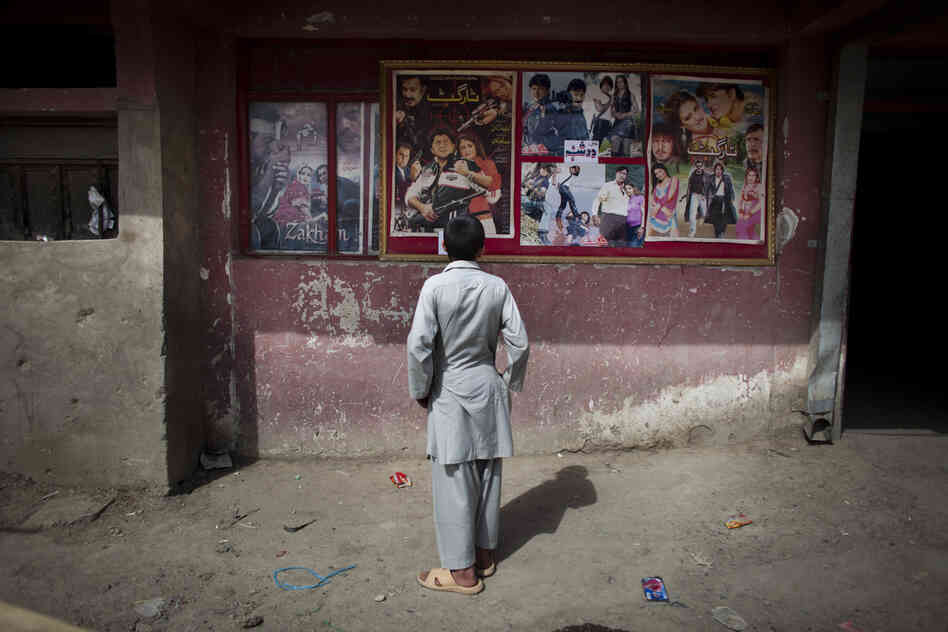 A young Afghan boy looks at movie posters outside Temorshahee Cinema in Kabul. Going to the movies, once banned under the Taliban, has become a popular form of entertainment in Kabul, but women and children rarely take part.