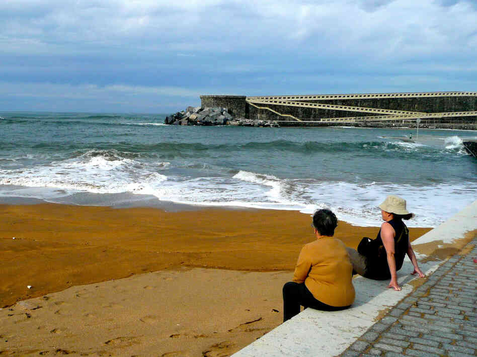Residents of Mutriku, a fishing village on Spain's northern coast, lounge at their local beach, protected from fierce Atlantic waves by a cement breakwater that also houses Europe's first wave energy plant.