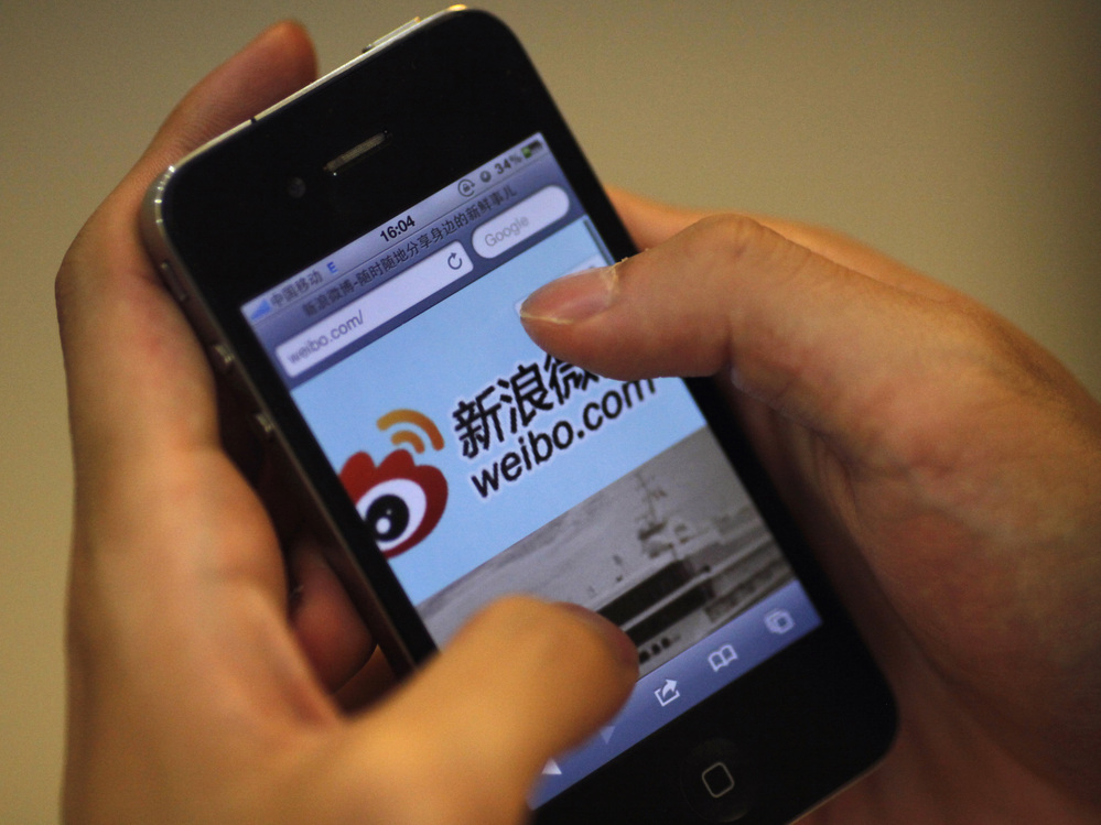 A man holds an iPhone as he visits Sina's Weibo microblogging site in Shanghai earlier this year.
