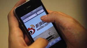A man holds an iPhone as he visits Sina's Weibo microblogging site in Shanghai earlier this year.