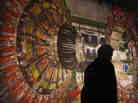 A worker walks past a giant photograph of the CMS detector of the Large Hadron Collider (LHC) at a 2008 science exhibition in Berlin, Germany. A worker walks past a giant photograph of the CMS detector of the Large Hadron Collider (LHC) at a 2008 science exhibition in Berlin, Germany.