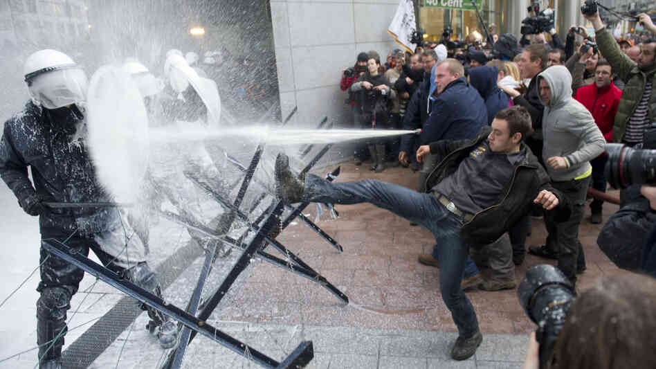 European dairy farmers spray police officers with milk during a demonstration outside the European Parliament in Brussels on Monday.