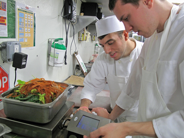 Glen Osterberg (right) and another line cook at Lupa learn how to use the LeanPath waste tracking software.